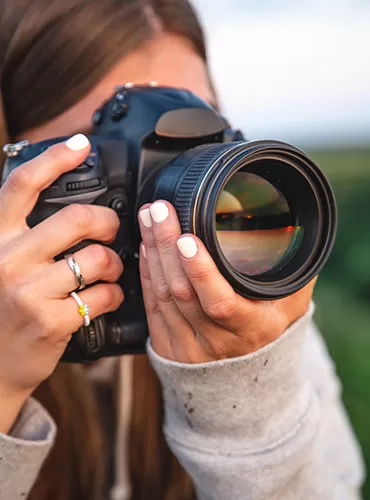 a young woman with a professional camera takes a photo in nature.